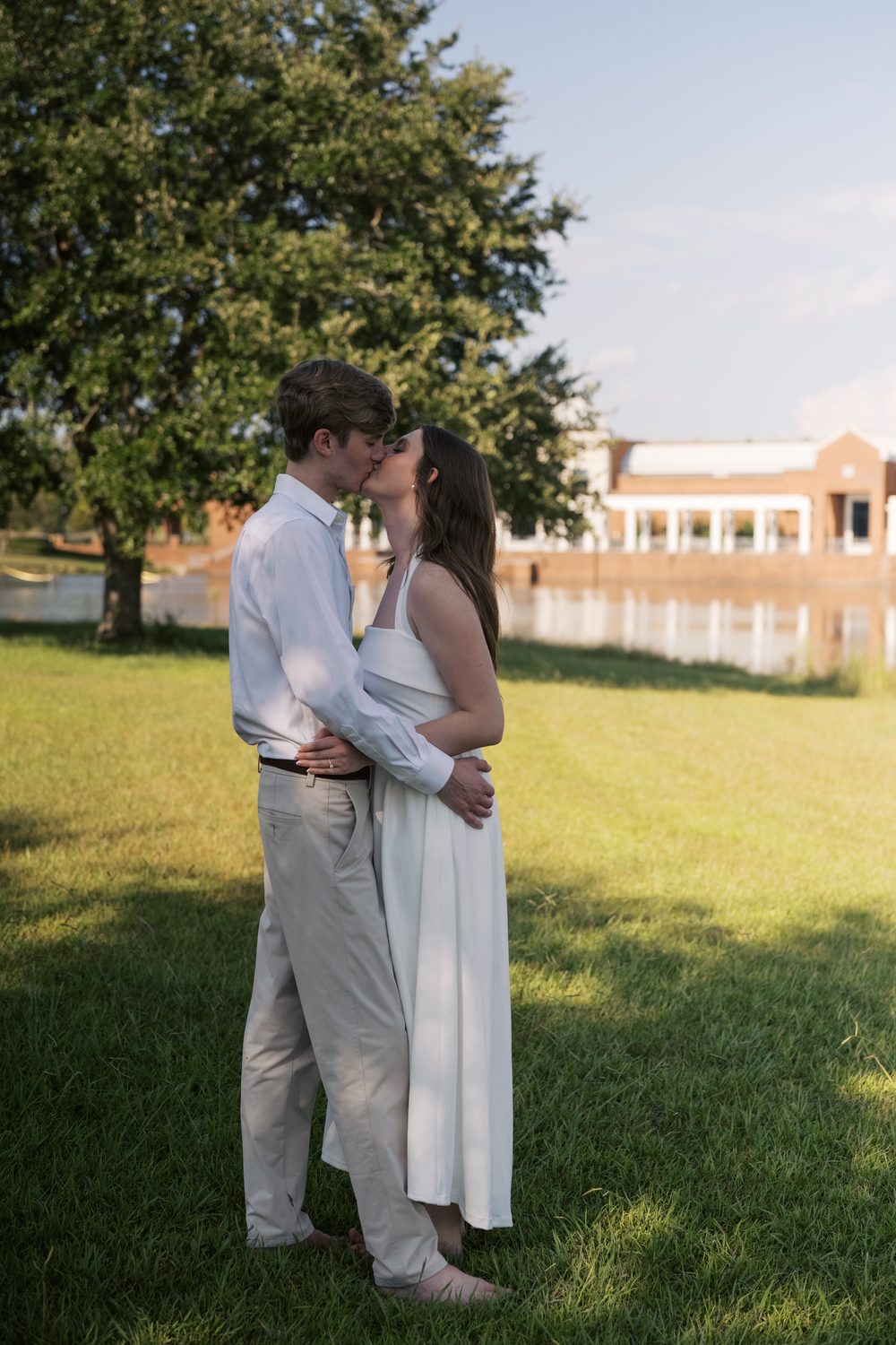 Colton and Ashlyn kissing under a tree beside the water.