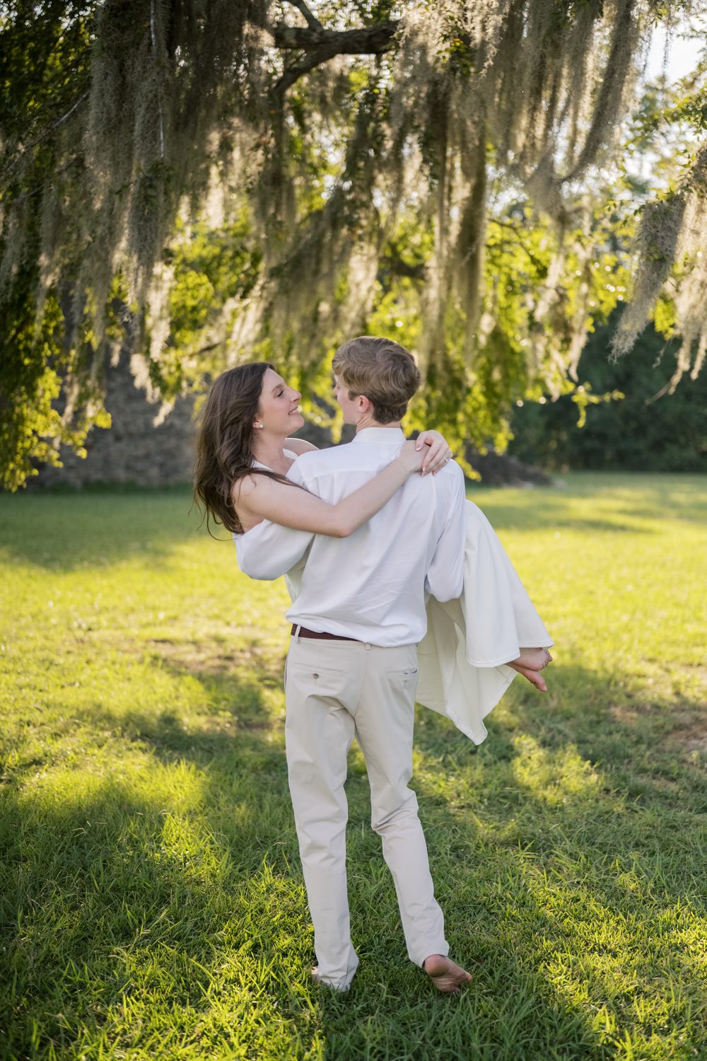 Colton lifting Ashlyn under a moss-draped oak.
